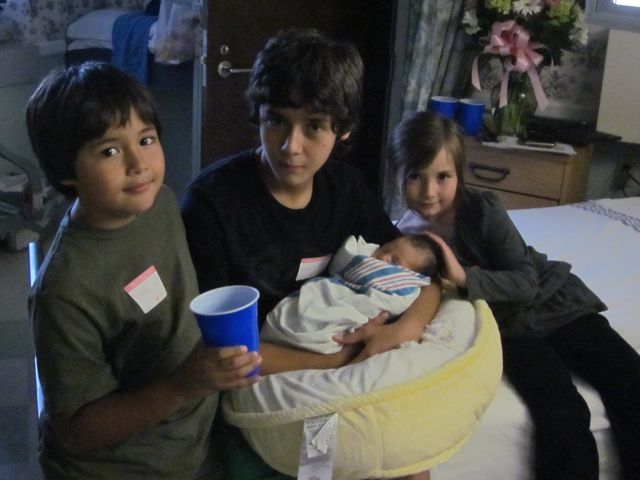 kids in hospital holding newborn baby cousin
